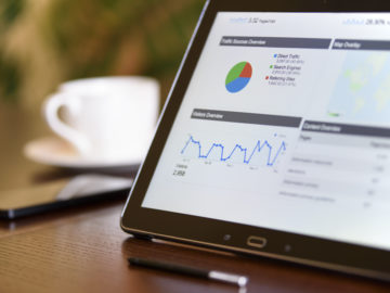 Business intelligence using modern technology Charts and analytical data on the tablet screen with a cup of coffee and a telephone in the background